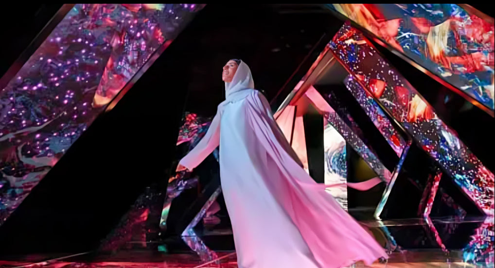 Woman in flowing attire walking through a vibrant, futuristic tunnel of light and color at AYA Universe Dubai.