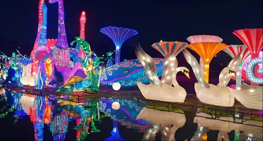 Stunning night display of glowing swans, flowers, and marine creatures reflecting on water at Dubai Garden Glow.