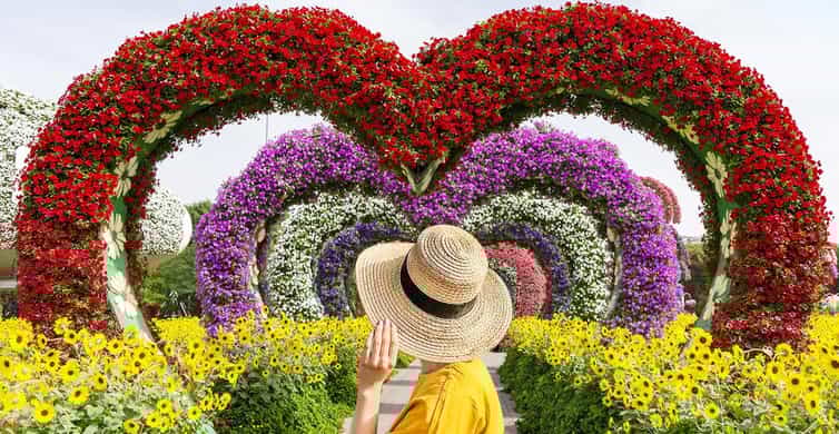Visitor admiring heart-shaped floral arches surrounded by vibrant blooms at Dubai Miracle Garden, the world’s largest natural flower garden.