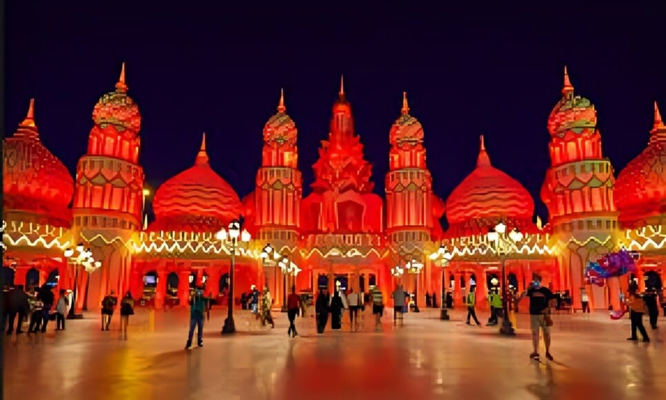 Stunning night view of Global Village Dubai entrance lit up in red, with visitors exploring the festive atmosphere and cultural architecture.