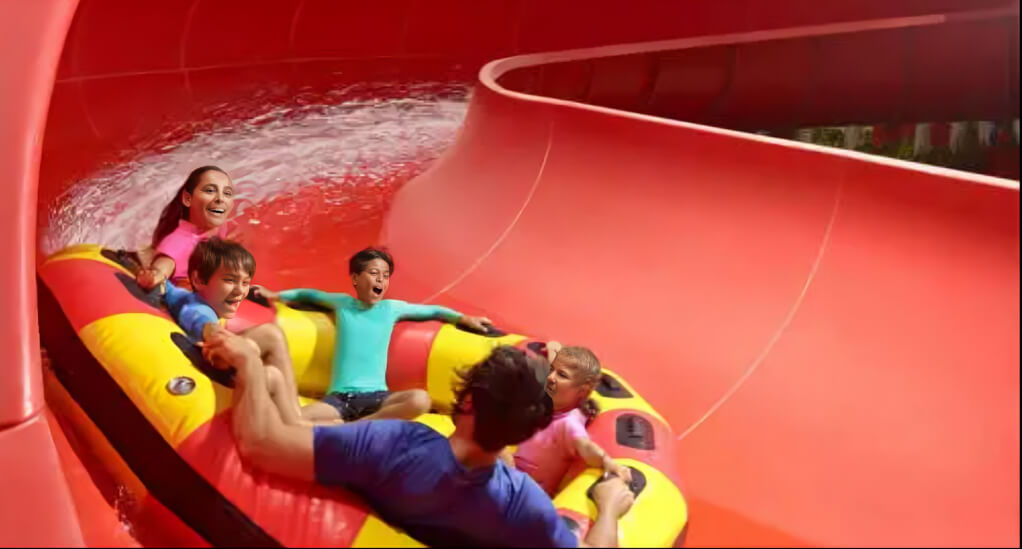 Families enjoying colorful tube water slides and splash rides at LEGOLAND Water Park Dubai, surrounded by vibrant play structures and sunny skies.