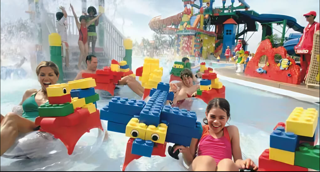 Kids and families enjoying the lazy river at LEGOLAND Water Park Dubai, floating on rafts built with giant colorful LEGO bricks in a playful, splash-filled setting.